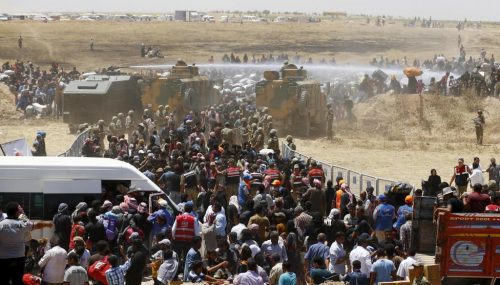 Turkish military use water cannon to stop Syrian refugees as they wait behind the border fences to cross into Turkey, near Akcakale in Sanliurfa province, Turkey, June 10, 2015.